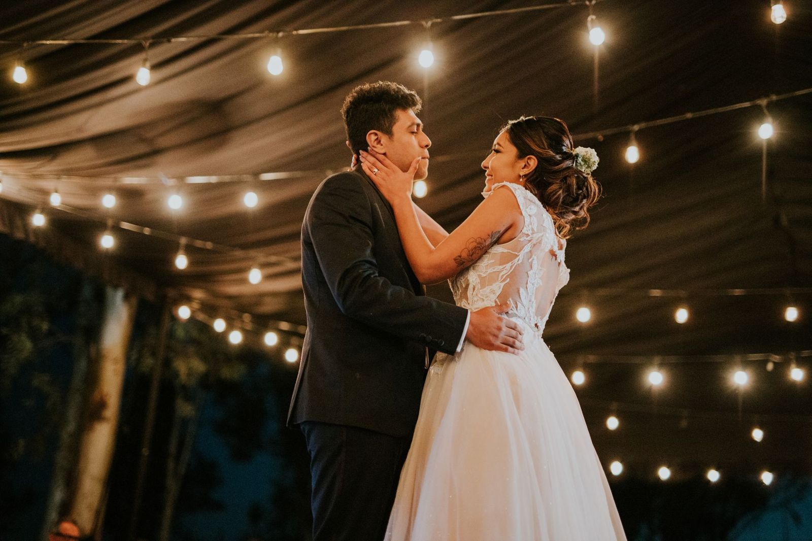 A warm first dance under string lights — the kind of frame clients buy as wall art